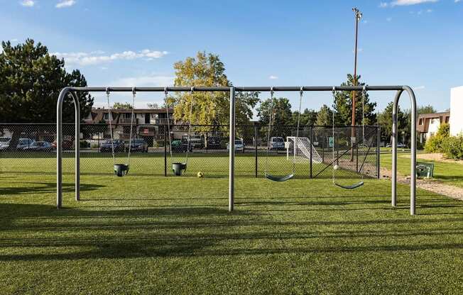 A playground with swings and a seesaw in the foreground.