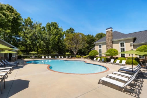 our resort style swimming pool is surrounded by lounge chairs and a building