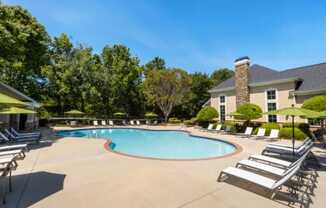 our resort style swimming pool is surrounded by lounge chairs and a building