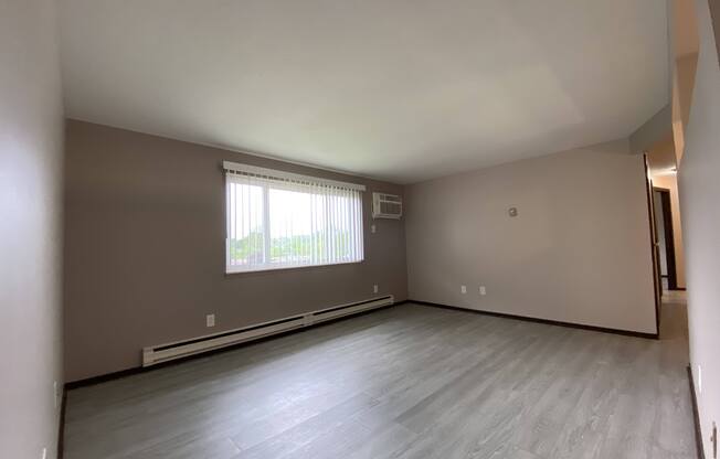 an empty living room with vinyl floors and a window