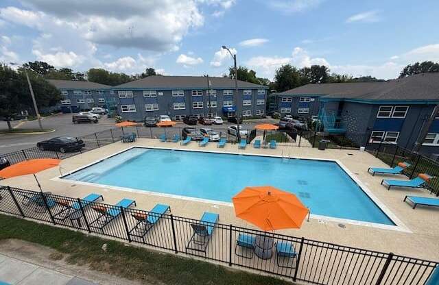The Canvas Nashville swimming pool surrounded by chairs and umbrellas with apartment buildings in the background.