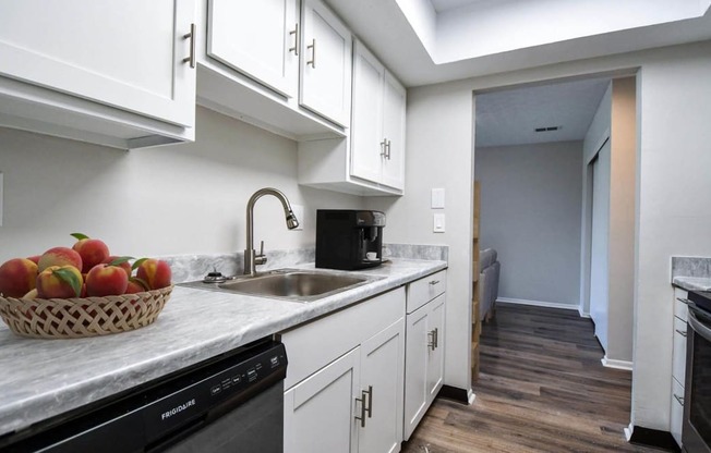 a kitchen with white cabinets and a bowl of fruit on the counter
