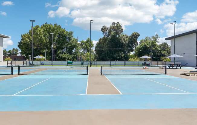 a tennis court with umbrellas and benches on a sunny day