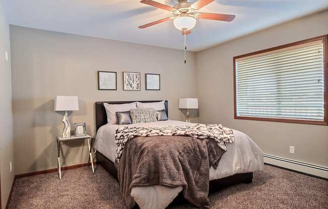 a bedroom with a large bed and a ceiling fan. Fargo, ND Urban Plains Apartments