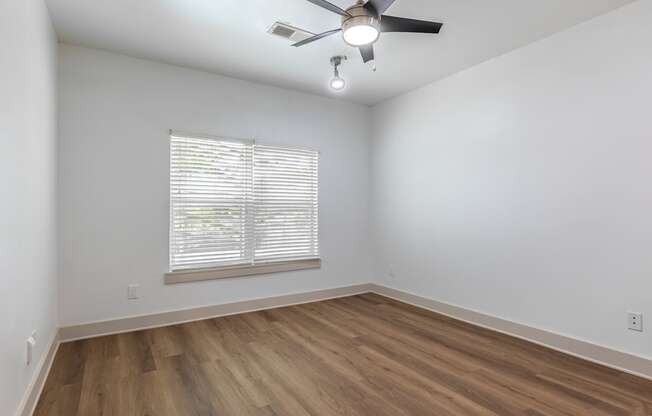 A room with a ceiling fan and wooden flooring.