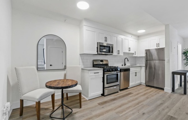 a kitchen with white cabinets and stainless steel appliances and a table