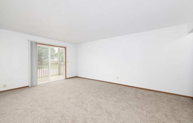 A room with a carpeted floor and a sliding glass door.