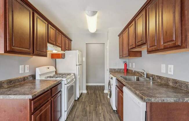 A kitchen with white appliances and brown cabinets.