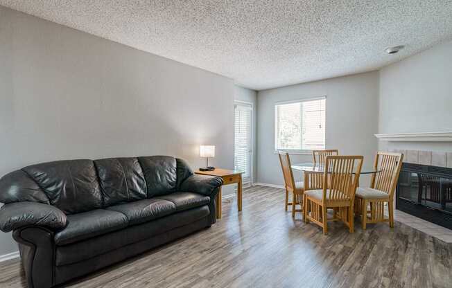 A black leather couch sits in a living room with wooden floors and furniture.