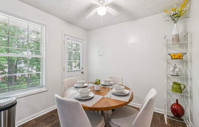 A dining room with a table set for two and a window with blinds.