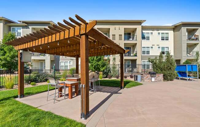 a patio with a pergola and tables in front of an apartment building