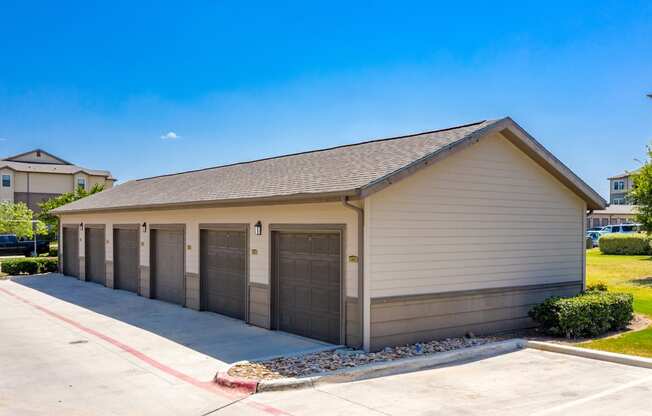 a small building with three garage doors on the side of a driveway