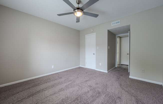 an empty living room with carpet and a ceiling fan