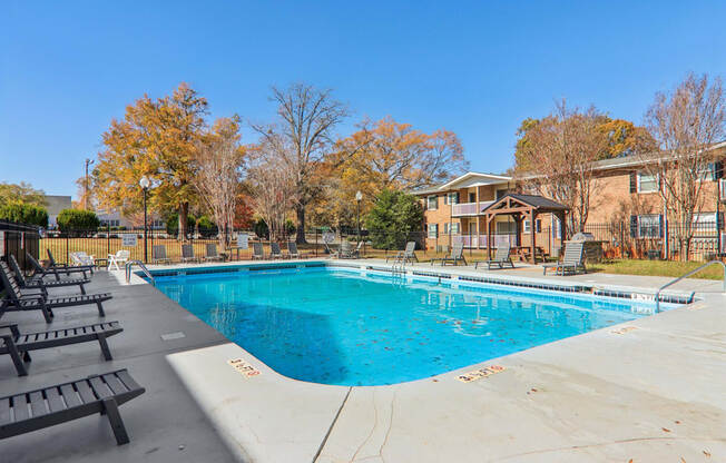 A swimming pool surrounded by trees and a building in the background.