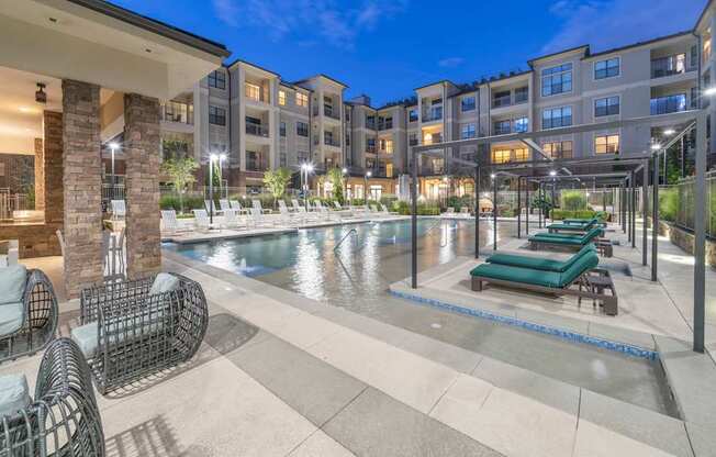 a swimming pool with lounge chairs in front of an apartment building at The Hendrix, Georgia, 30329