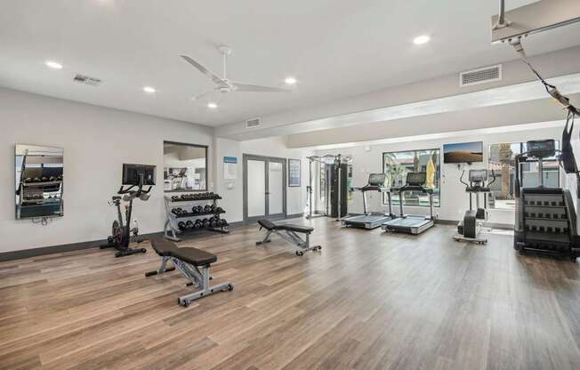 a fitness room with weights and cardio equipment on a wooden floor