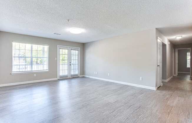 A spacious room with wood flooring and a large window.