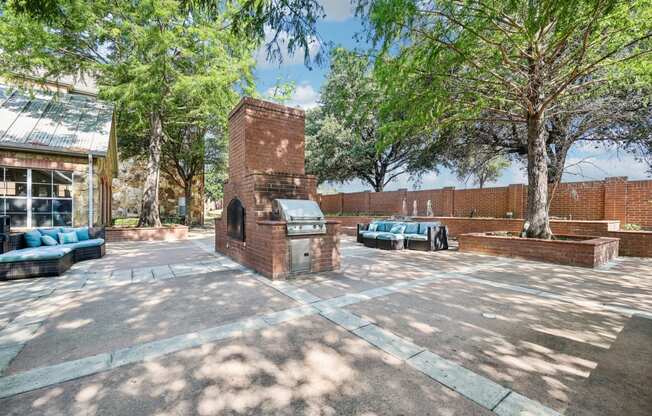 a courtyard with trees and a brick building with a grill