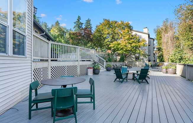 A wooden deck with green chairs and a table.