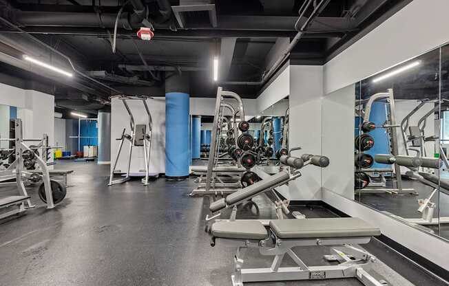 A gym with a variety of equipment including weights and a bench.