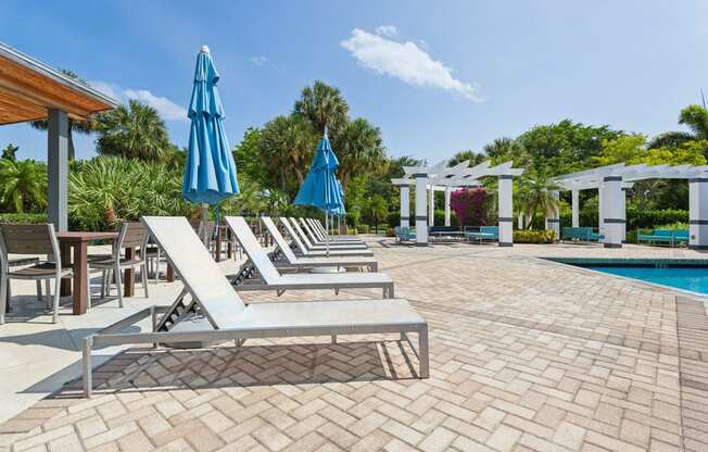 a pool with lounge chairs and umbrellas next to a pool