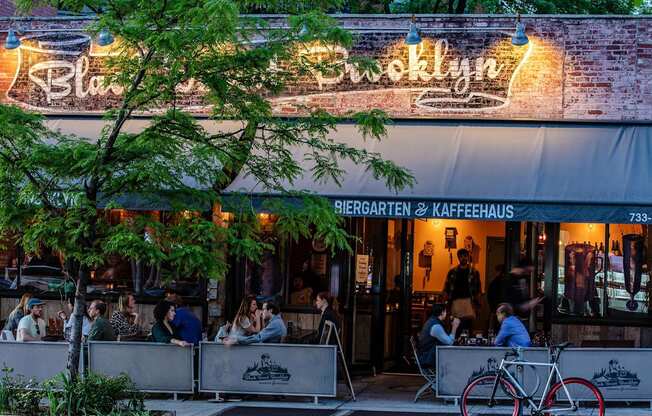 people sitting at tables outside of a restaurant at The Paxton, Brooklyn, 11201