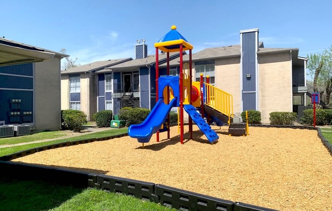 A playground with a blue and yellow slide at Pine Creek Apartments in Houston, TX