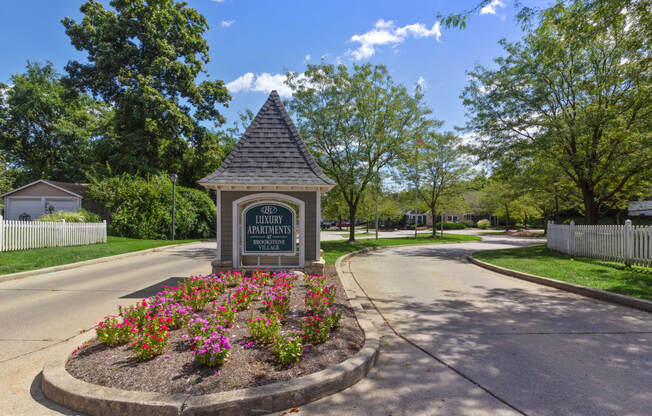 the welcome sign at the end of a street in a neighborhood with trees