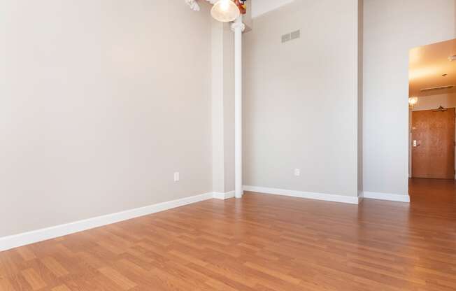 an empty living room with wood floors and white walls
