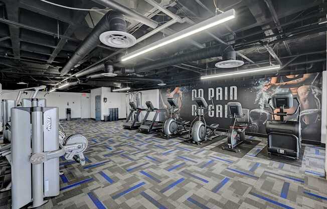 A gym with a variety of equipment including a rowing machine, a treadmill, and a weight bench.