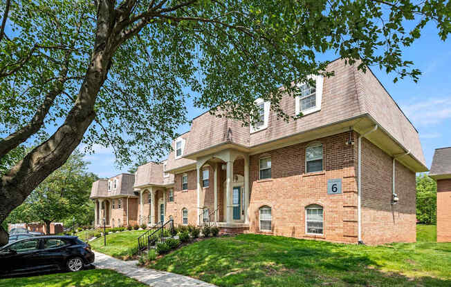 A house with a brick facade and a tree in front.