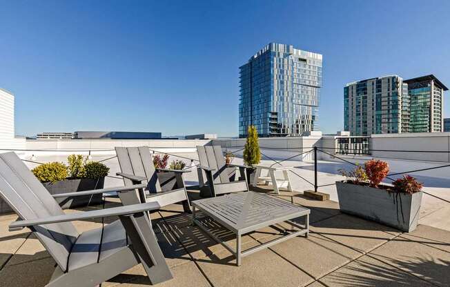 A patio with chairs and a table with a view of buildings in the background.