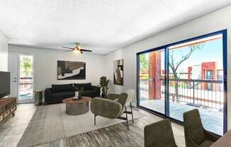 A living room with a black couch, a grey armchair, a coffee table, and a ceiling fan.