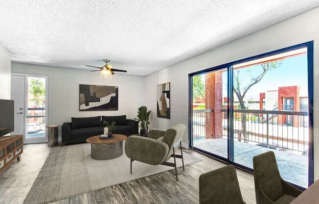 A living room with a black couch, a grey armchair, a coffee table, and a ceiling fan.