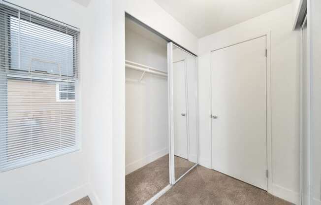 an empty bedroom with a closet and a window