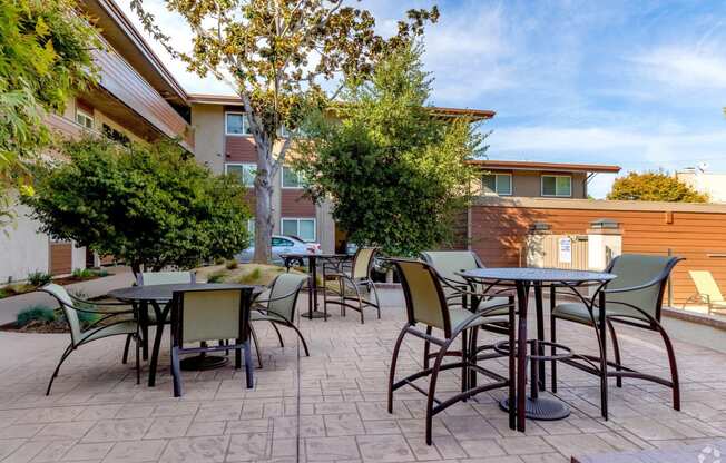 an outdoor patio with tables and chairs and trees