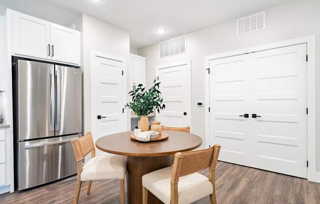 a dining room with a table and chairs and a stainless steel refrigerator