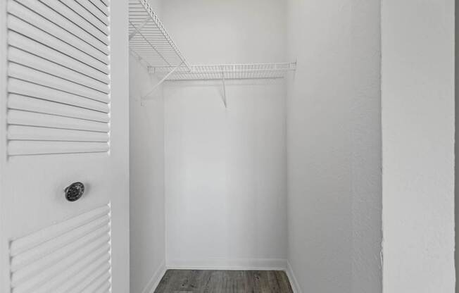 a walk in closet with white walls and a white closet door