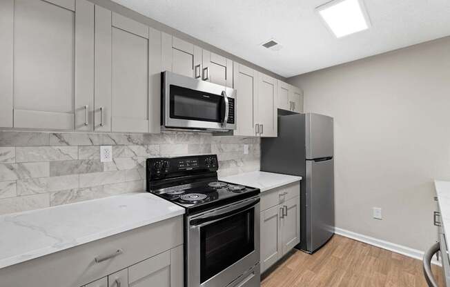 A kitchen with a stove, oven, refrigerator, and microwave.