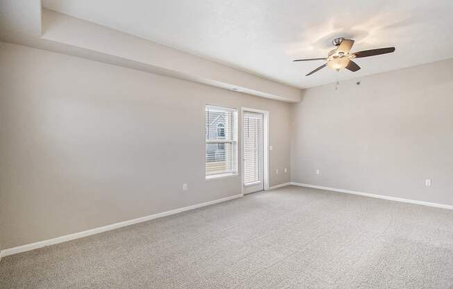 An enlarged living room with a ceiling fan and plush carpeting at Lynbrook Apartments and Townhomes, Elkhorn, NE, 68022