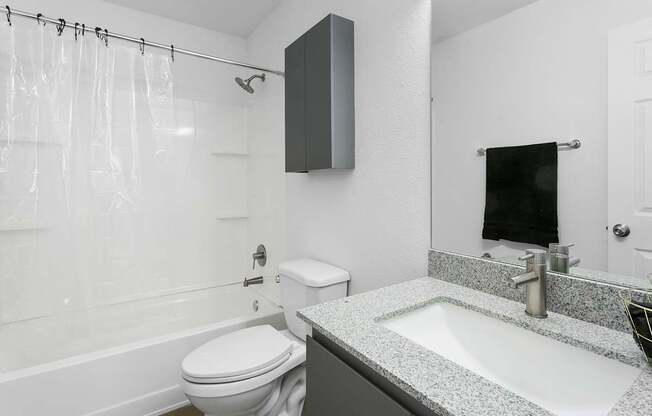 A white toilet sits next to a white bathtub in a bathroom.