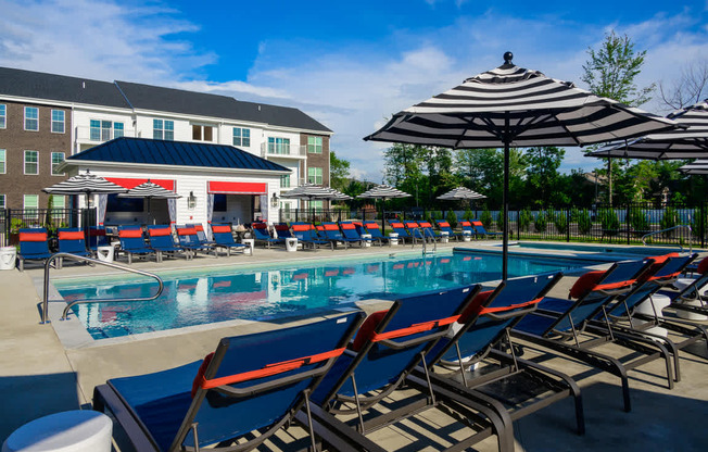 A pool with sun loungers and a building in the background.