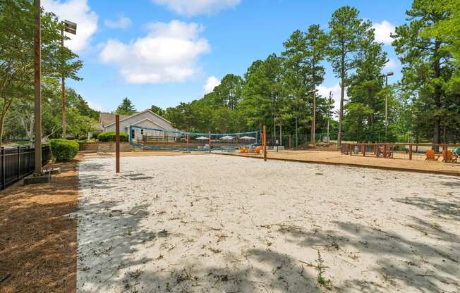 A sandy area with trees and a building in the background.