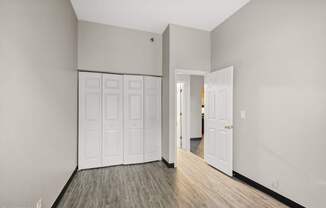 the living room of an empty apartment with white doors and wood flooring
