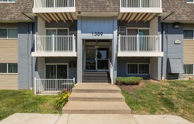 the front of an apartment building with stairs and a porch