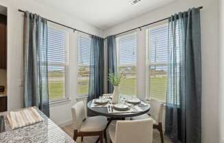A dining room with a table set for two and a view of the outdoors.