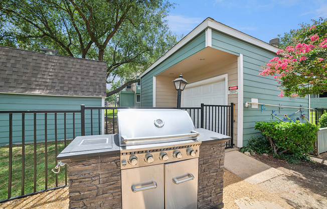 A house with a blue exterior has a silver grill on a stone pillar.