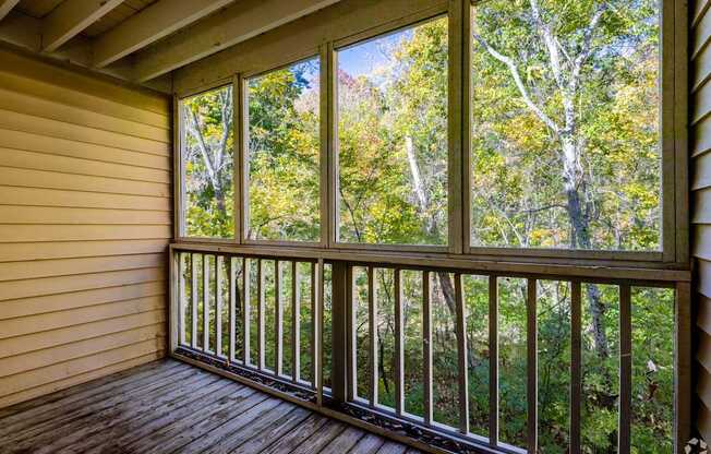 a screened in porch with a view of the woods