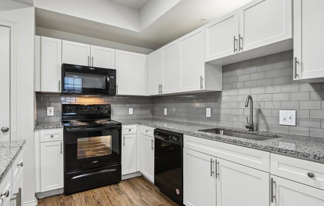 A kitchen with black appliances and white cabinets.