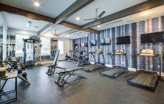 A gym with treadmills, weights, and exercise equipment.